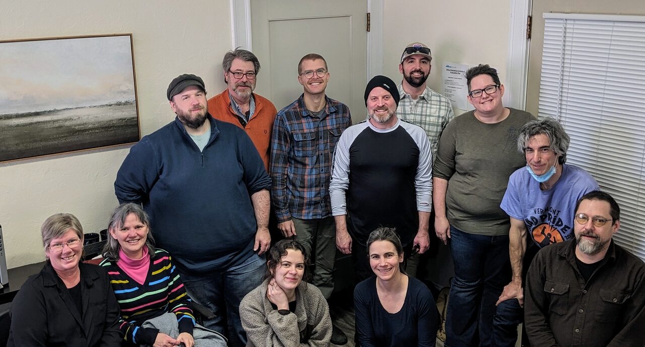 Photo of 12 people, some standing, some kneeling. Everyone is smiling at the camera.